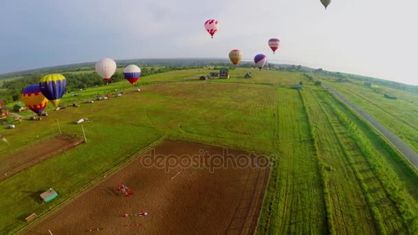 Several air balloons flying above fields — Stock Video