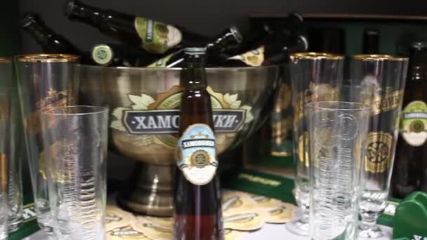 Bierflaschen mit Gläsern im Regal — Stockvideo