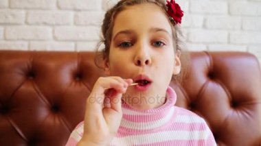 Güzel kız kanepede kapalı portakal lolipop oturur yalıyor