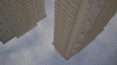 Yüksek binaların yansıması ile su birikintisi ve kız bacakları su