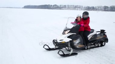 Mutlu kızı ve anne kask kış gününde skidoo üzerinde binmek