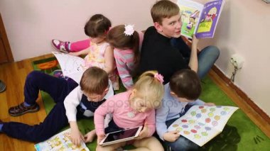 Moskova, Rusya - 28 Nisan 2015: Altı çocuk katta bir daire içinde onların el, okuma ve görünüşe göre ders kitapları ile kamera oturmak