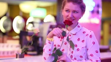 Genç ve güzel kadın tutar ve kırmızı gül restoran olarak burnunu çekmek