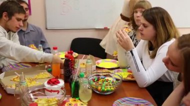 Dokuz genç masada oturup yemek sırasında doğum günü