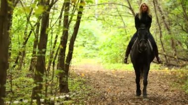 Sarışın genç kadın içinde siyah sürmek at yeşil park