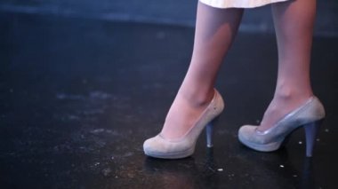 Yüksek topuklu siyah zemin üzerinde yan yana yürüyen bir kadın