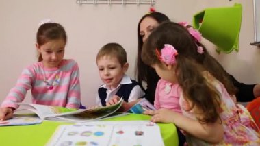Moskova, Rusya - 28 Nisan 2015: Dört çocuk ve bir öğretmen masaya otur ve ders kitapları İngilizce olarak görünüyor