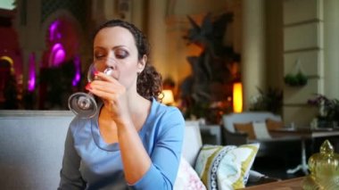 Kadın şarap, gülümsüyor ve içecekler ile cam restoranda tutar.