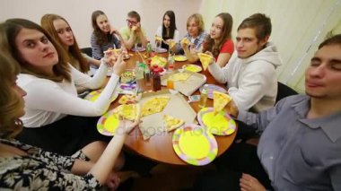 On gençler masaya oturmak, konuşan ve doğum gününe pizza yemek