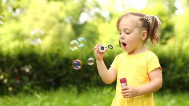 Sarı sevimli küçük kız sabun köpüğü yeşil park darbeler.