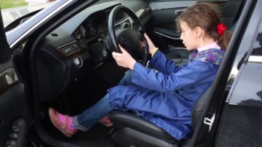 Arabada tekerlek üzerinde el ele tutuşarak sürücü koltuğuna oturan kız