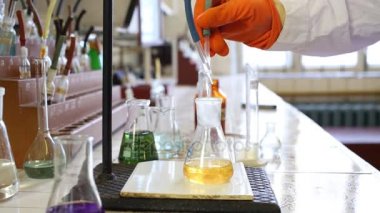 Ellerinde eldiven damlar sıvıyla laboratuarında sarı sıvı şişesi içine