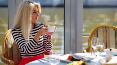 Gemi Restoran masada oturan ve bardağı içme singlet sarışın.