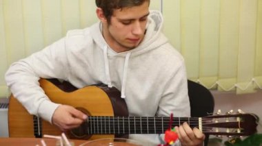 Çocuk genç gitar çalıyor ve tablo odasında şarkı söylüyor