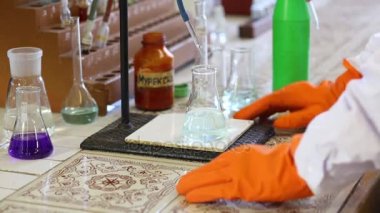 Turuncu eldiven eller sıvı ile şişeyi al. Şişe üzerinde metin: murexide