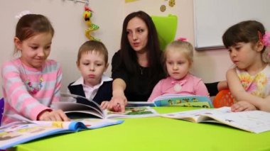 Moskova, Rusya - 28 Nisan 2015: Bir öğretmen ve dört çocuk göz İngilizce ders kitabı, öğretmen bir kitapta puan parmak