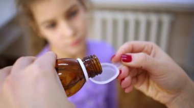 Kadın doktor ilaç şurubu içine plastik ölçme kaşık dökülen ve küçük kız verir.
