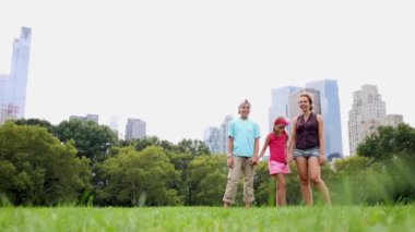 İki çocuk ve anneleri çimenli çimenlikte, düşük açılı görünüş çalıştırmak.