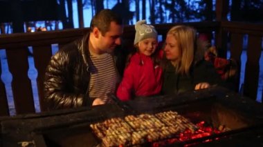 Baba, anne ve kızı kış geceleri et ile barbekü yapmak