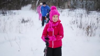 Üç çocuk ve iki yetişkin ile kış gününde kayaklar üzerinde gidiyor. Kız üzerinde odaklanın. Kız kutup tutar