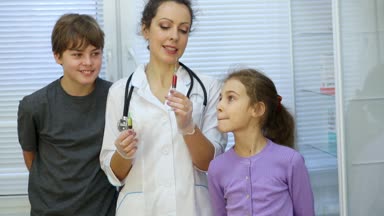 Kadın doktor ilaçlarla birlikte iki şırınga tutar ve onlar hakkında yakın durmak çocuklara söyler.