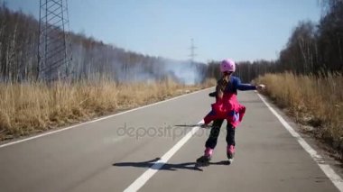 Kız paten ve genç çocuk yolda geliyor Bisiklet park çimenlerde yanma için.