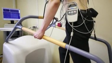 Elektrokardiyogram filmini çekerken bir koşu bandı üzerinde yürüyen genç adam