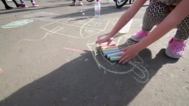 Bacaklar ve parlak tebeşir asfalt üzerinde çizim için hazırlanıyor ile küçük kızın elleri
