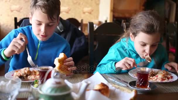 男孩和女孩吃肉与蔬菜坐在桌在咖啡馆 — 图库视频影像