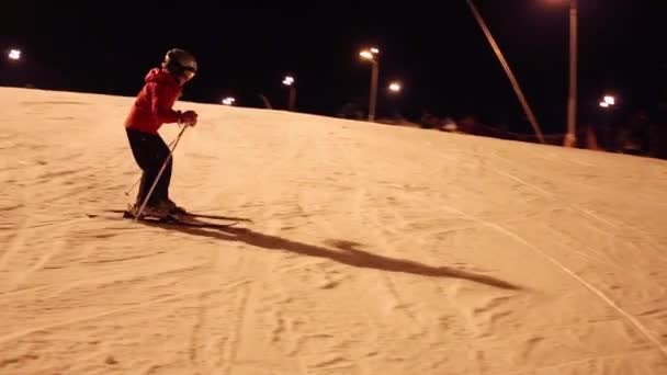 女孩滑雪者在头盔慢慢地在斜坡上晚上 — 图库视频影像