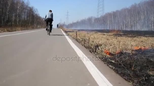 Muž Jedoucí Kole Cestu Podél Vypalování Suché Trávy — Stock video