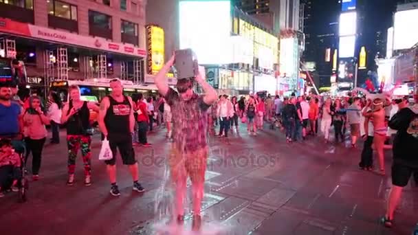 ニューヨーク アメリカ合衆国 2014 人が見て ブロードウェイで夜の時間で彼の頭の上に段ボールのバケツから冷たい水を注ぐ男の写真を撮る — ストック動画