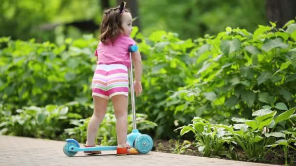 小可爱的女孩大拇指在附近的滑板车在夏季公园 — 图库视频影像