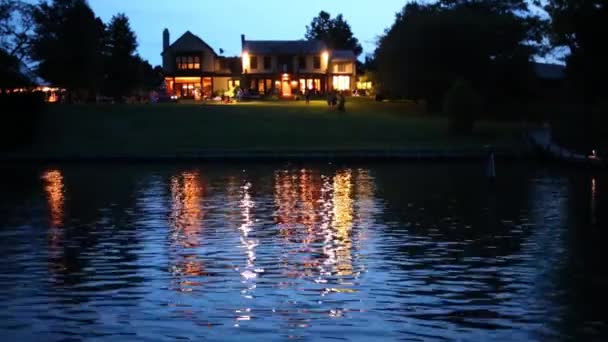 夜の海岸に照らされたコテージと湖で木製の桟橋 — ストック動画