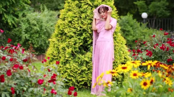Жінка Рожевому Сарі Серед Квітів Торкаються Гілок Альтанки — стокове відео