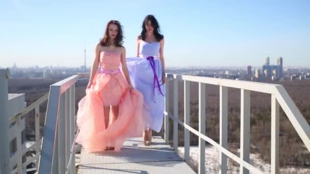女孩穿着粉红色和蓝色的礼服 拿着他们的裙子在屋顶上着陆 — 图库视频影像