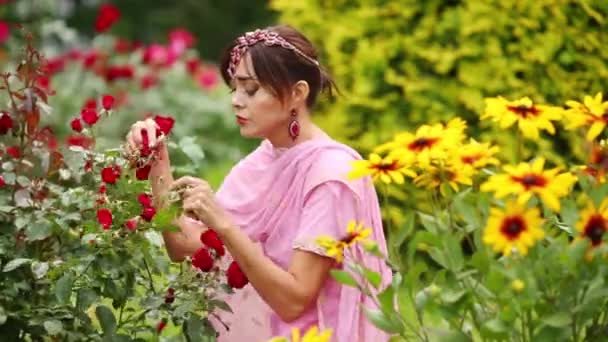 Kvinna Rosa Sari Sitter Blommor Och Röra Och Lukta Rosor — Stockvideo