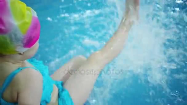 游泳帽上的小女孩在水池的水里挣扎着脚 — 图库视频影像