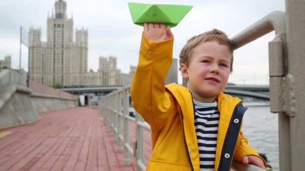 一个男孩在河堤上玩绿纸船 — 图库视频影像