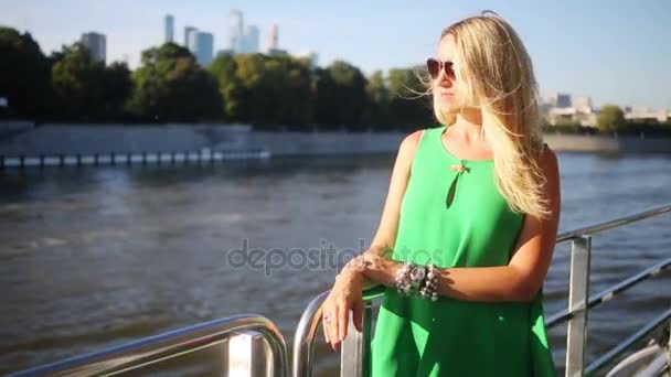 妇女在太阳镜和绿色礼服站立在船的扶手在河航行 — 图库视频影像