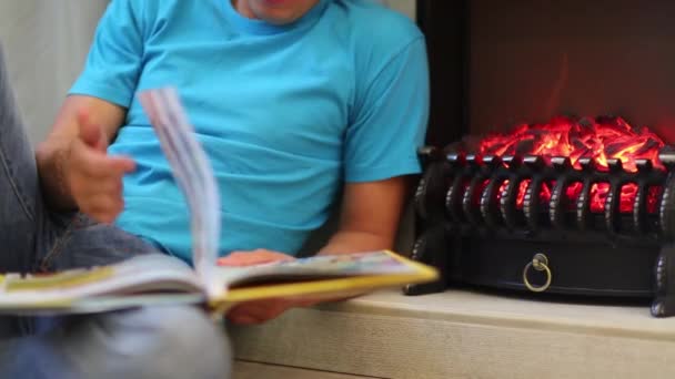 Homem Sentado Junto Lareira Folheando Livro — Vídeo de Stock