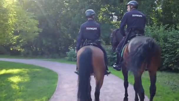 モスクワ 2015 ヘルメットの日当たりの良い緑豊かな公園 公園ソコルニキの特別警察隊のパトロールの つの馬警官の裏 — ストック動画