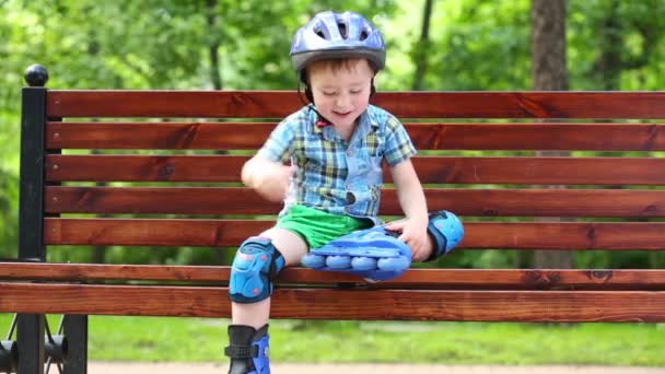 Kleiner Junge Rollerblades Sitzt Auf Bank Und Spielt Sommerpark — Stockvideo