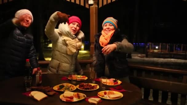 两个女人和男人站在餐桌上 在冬季晚上来到这里在乔木 — 图库视频影像