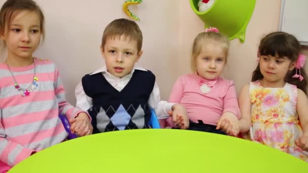 Cuatro Niños Sentados Una Mesa Tomados Mano Para Levantarlos Bajarlos — Vídeos de Stock