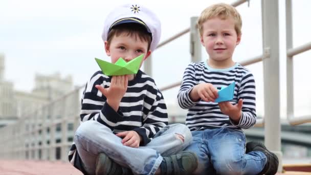 Δύο Αγόρια Καθίσει Ανάχωμα Και Παίζοντας Σκάφη Χαρτί — Αρχείο Βίντεο