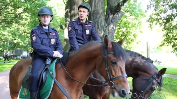 ヘルメット緑豊かな日当たりの良い公園 公園ソコルニキの警察のパトロールでモスクワ 2015 馬人の警官 — ストック動画