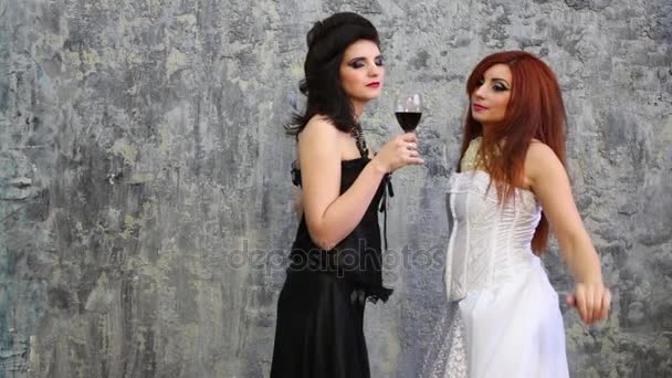 白と黒のドレスで 人の可愛い女性の壁の近くのワインでポーズを取る — ストック動画