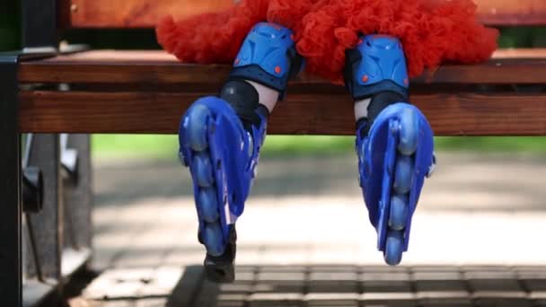 Benen Van Het Meisje Rolschaatsen Zittend Bank Bij Zomerdag — Stockvideo