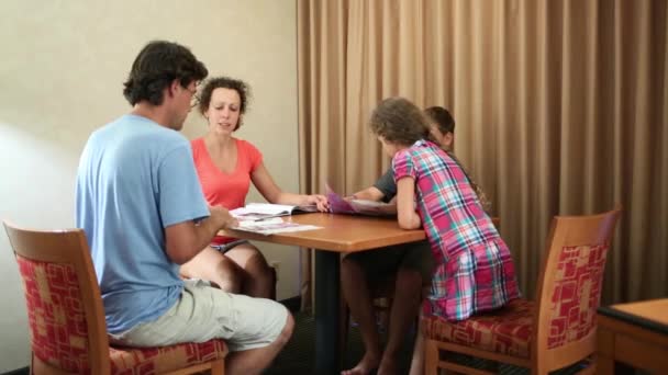 Τετραμελή Οικογένεια Κάθεται Στο Τραπέζι Και Διαβάζει Περιοδικά — Αρχείο Βίντεο